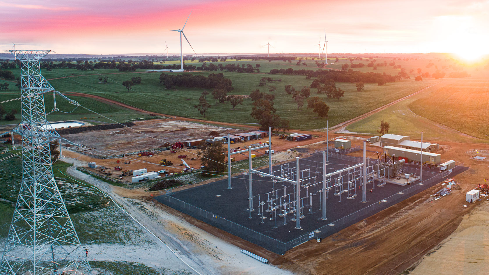 Electricity substation with wind turbines in the distance at sunset