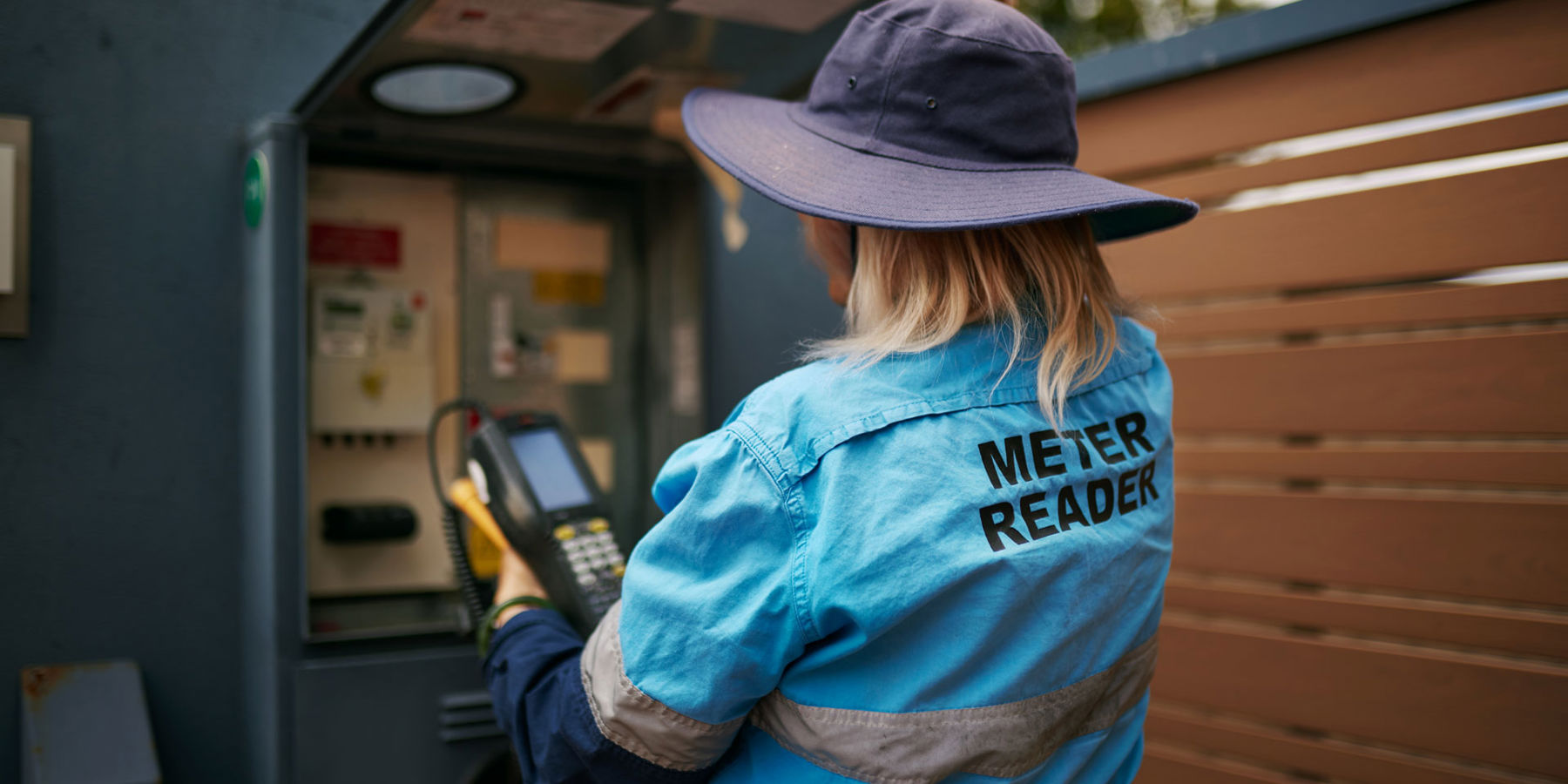 A female meter reader reading a Western Power meter on a residential property