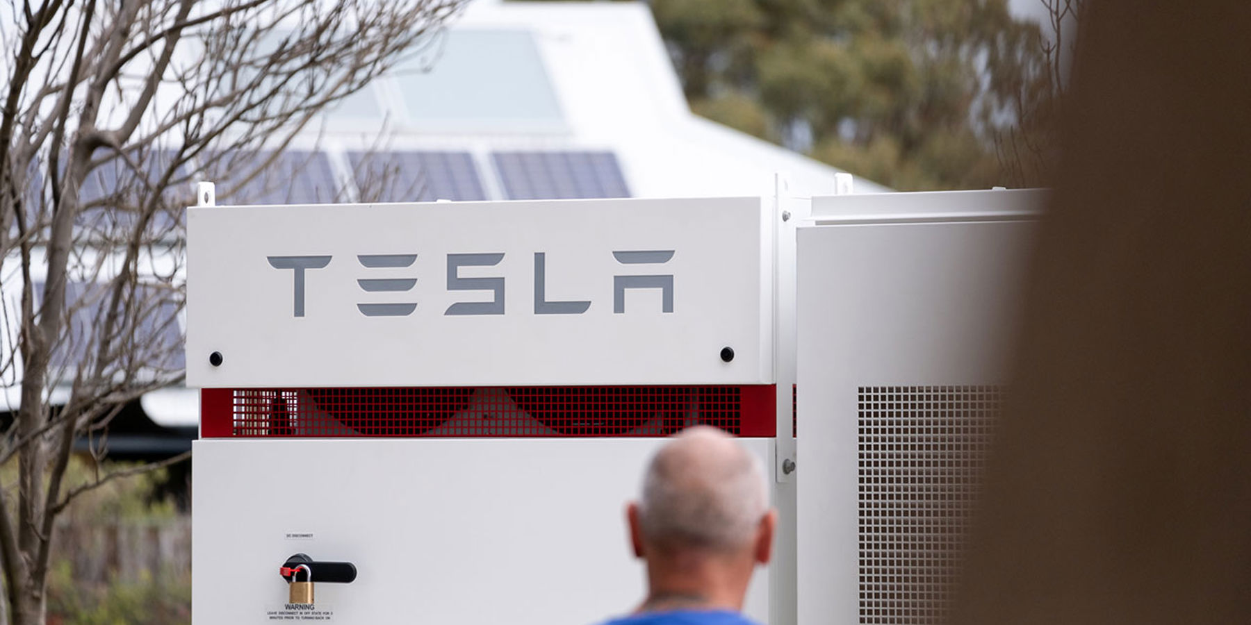 man standing front of tesla battery